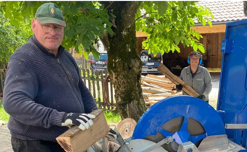 Zwei Personen arbeiten gemeinsam an einem Holzspalter