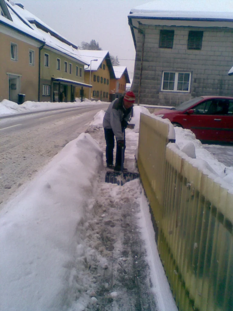 Eine Person räumt Schnee von einem Gehweg
