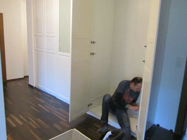 Ein Mann arbeitet kniend an einem eingebauten Schrank.